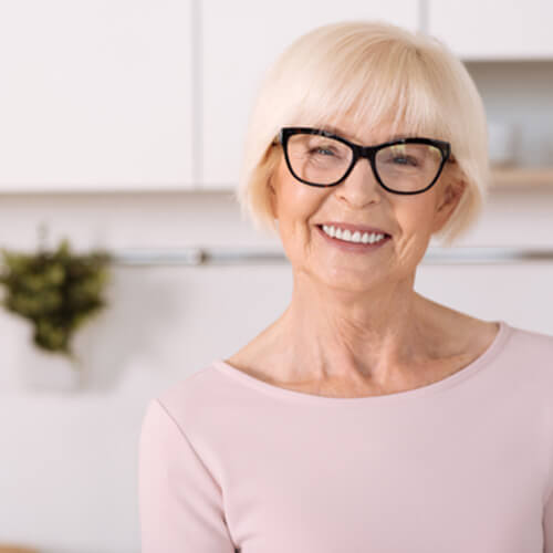 Senior woman smiling with glasses and light pink shirt