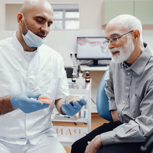 A dentist explaining how to adjust to dentures to a patient