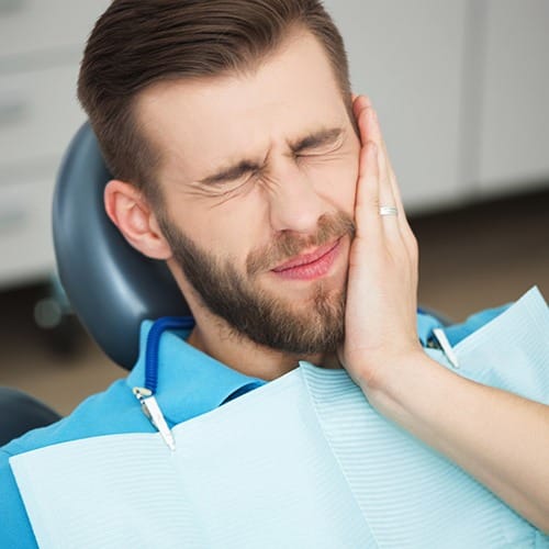 Man holding cheek during emergency dentistry treatment