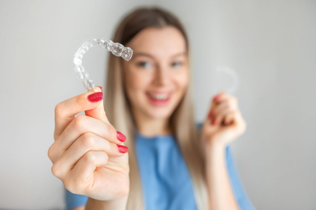 Woman with red nails holding out Invisalign